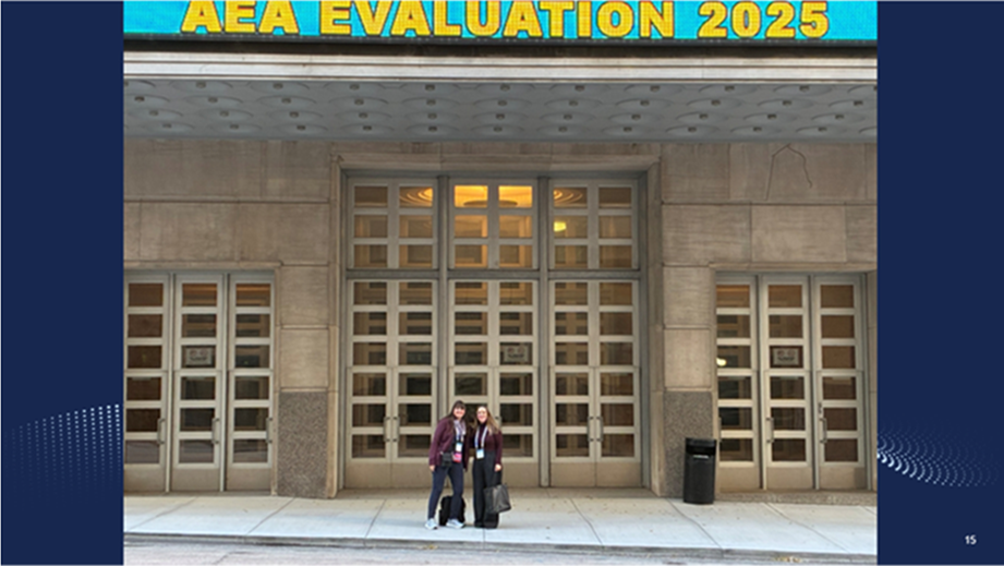 Laura Milazzo and Emelie Bailey stand in front of the Kansas City Conference center building with the AEA Evaluation 2025 billboard overhead.