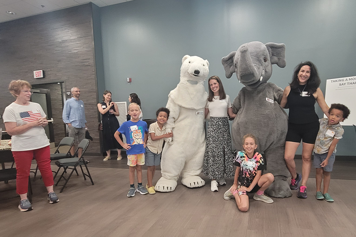 Kids and adults posing with the Columbus Zoo's polar bear and elephant mascots. People are conversing in the background as the GRC's 15th year anniversary concludes!